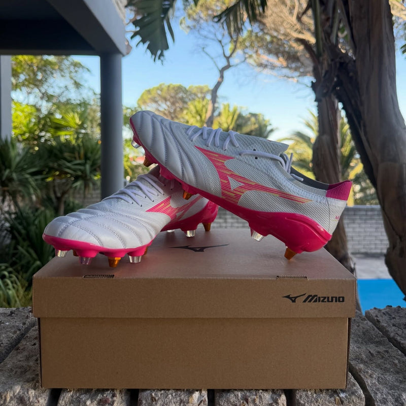 White and pink Mizuno Morelia rugby boots resting on a Mizuno shoebox outdoors